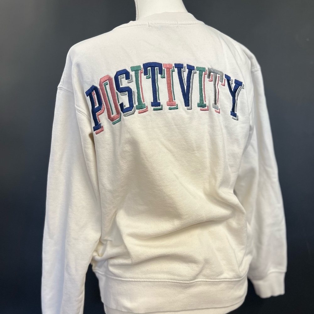 Social Scene White sweater with the words “Positivity” on the front and back.